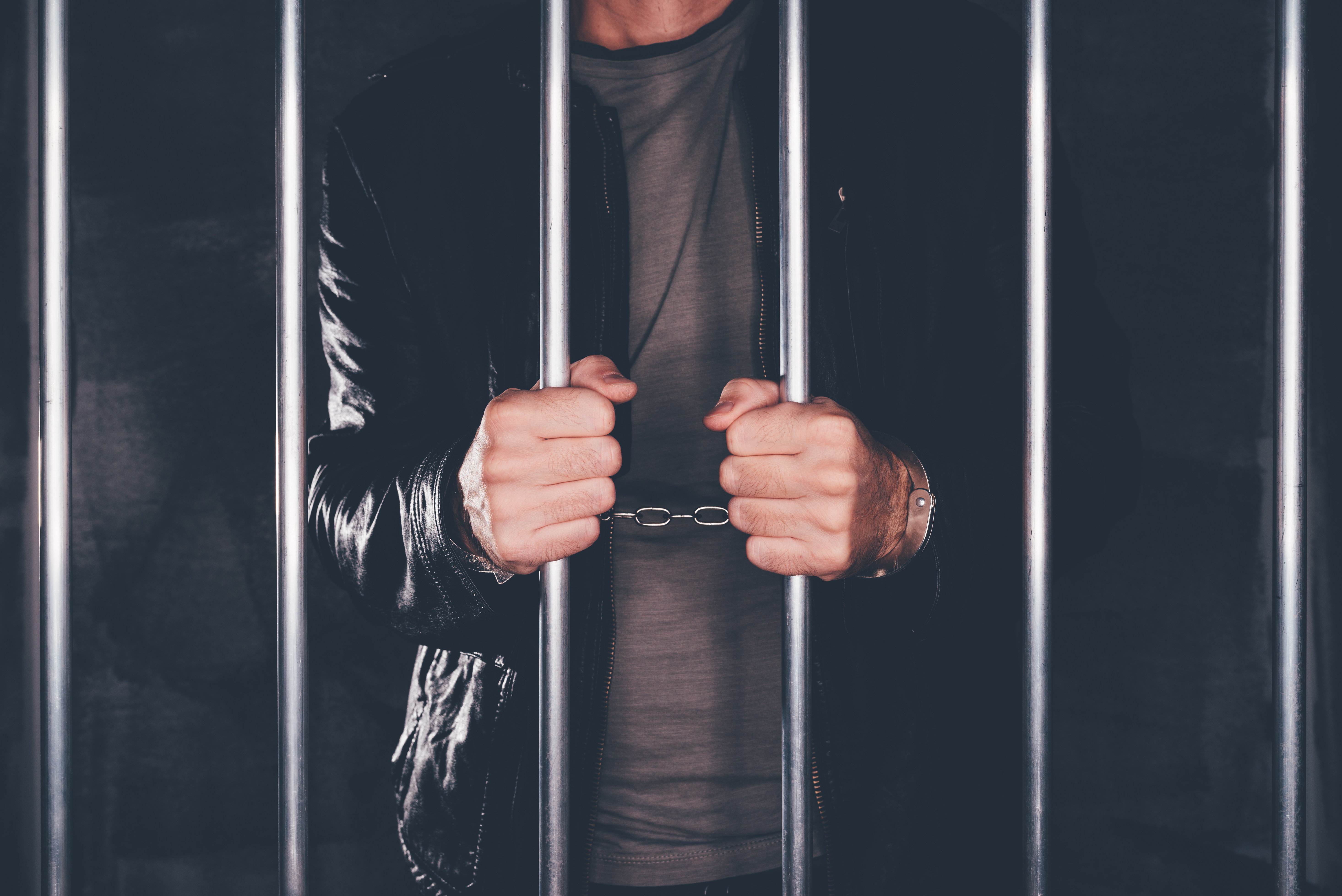 Handcuffed man behind prison bars